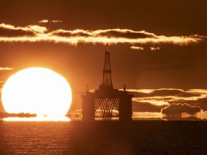 An oil rig out at sea at sunset