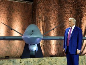 US President Donald Trump stands backdropped by an MQ-9 Reaper drone before addressing military personnel at the Al Udeid Air Base in Doha, Qatar