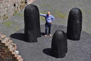 Artist David Nash with his new sculpture called Three Black Humps