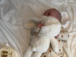 Tomas cuddling a toy on a white sheet