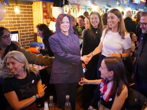 People pose for photos with a cardboard cutout of Kamala Harris (Yui Mok / PA).
