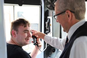 Harry using the Tannoy in the guard's compartment, supported by Volunteer Coordinator Phil Liddell. Photo: Derwen College