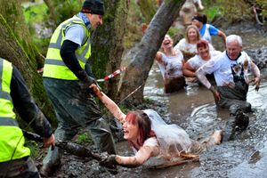 Karen Bill being helped from the muddy pool
