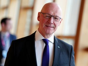 John Swinney smiling in a corridor at Holyrood