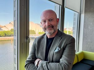 Head and shoulders photo of Howard Simpson smiling in an office overlooking the Clyde
