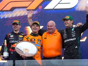 Lando Norris holds the victory shield in Melbourne with Max Verstappen and George Russell standing either side of him