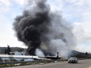 Smoke rises from a factory hit during clashes by Syrian security forces and gunmen loyal to former president Bashar Assad