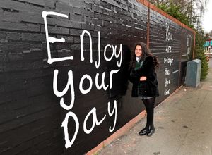 Neriyah Faith Spencer poses next to a mural of the positive messages she has been putting out