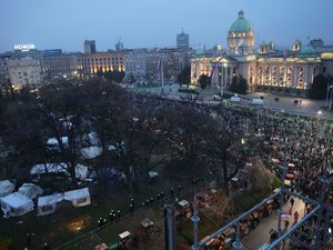 Protesters walk past the Parliament building