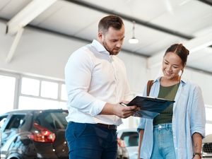 A car buyer discusses finance options with a dealership representative. New research suggests many UK drivers now regret the car finance deals they agreed to in the past decade.