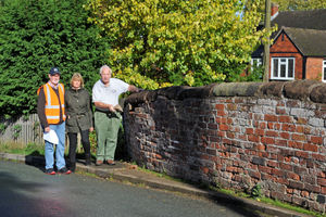 Bob Wood, Rosalind Wells and Bob's father, Joseph Eric Wood, next to a wall on Burton Road, which has been damaged due to lorries trying to reverse along the narrow road