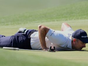 Justin Rose lies on the eighth green to line up a putt