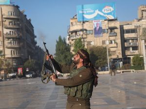 A Syrian opposition fighter shoots in the air in Aleppo