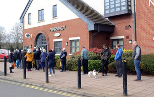 Queuing a metre apart outside the pharmacy.