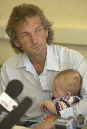 Natalie's father David Putt, holding her son, Rhys McCallum at a press conference in 2003