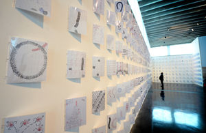 Part of the exhibition features over 1000 pieces of laminated paper stuck to the walls with different rubber stamp artwork on them
