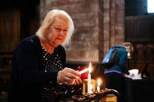 Susan Smithson lights a candle at at Shrewsbury Abbey