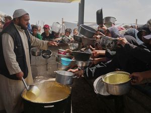 Palestinian children and women struggle to get donated food at a community kitchen in Khan Younis, Gaza Strip