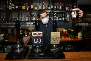 The bar manager of the White Hart Pub in Ironbridge checks the first pint poured after reopening