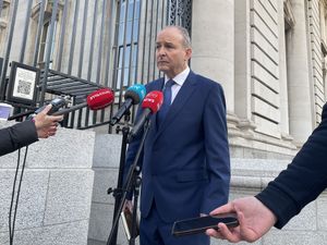 Micheal Martin standing outside, speaking into several microphones