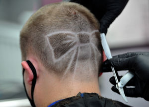 Stylist Luke Hay etches the bow into the back of Ellie's head