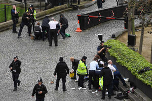 A policeman points his gun at a man on the floor outside the Palace of Westminster while Pc Keith Palmer is treated nearby