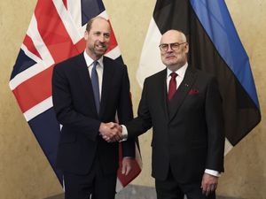 The Prince of Wales (left) shakes hands with the President of Estonia Alar Karis in front of a UK and an Estonian flag