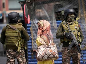 Indian soldiers stand guard as a woman walks in a market in Srinagar, Indian controlled Kashmir