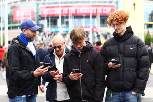 Football fans check their phone's as they receive an emergency alert test text from the UK Government during the Premier League match between AFC Bournemouth and West Ham United at Vitality Stadium on April 23, 2023 in Bournemouth, England. (Photo by Clive Rose/Getty Images)