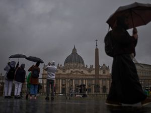 Tourists and locals walk in St Peter’s Square on a rainy day at the Vatican