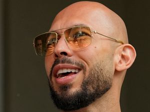 Headshot of Andrew Tate smiling, while wearing sunglasses