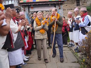 Edward and Sophie, adorned with yellow garlands, are greeted by villagers