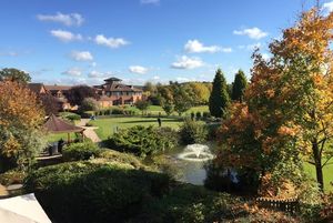 Autumn view across the grounds of the Abbey Hotel Golf and Country Club in Redditch, with landscaped gardens, water feature and hotel buildings in the background.