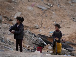 Displaced Palestinian girls fill a plastic jerrycan with water