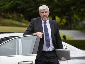 John O'Dowd leans on the door of a car