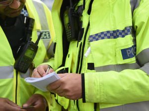 A police officer wearing a high-vis jacked writes in their notebook