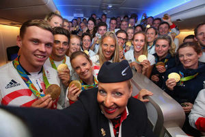 Joe Clarke, left, joins gold medalists of Team GB to pose for a selfie with a member of British Airways cabin crew