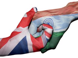 Two interlocking hands, one on the left coloured with the Union flag, and the one on the right coloured in the Indian flag