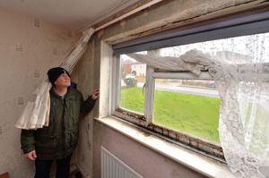 John Fones next to some of the damp in his home