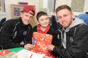 Shrewsbury Town Players James Caton and Jordon Clark give a present to Oliver Cox, 11, from Llanfyllin