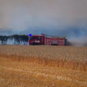 A fire engine speeds across a field towards the fire.