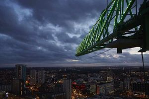 View of the lit crane jib and Birmingham city at dusk