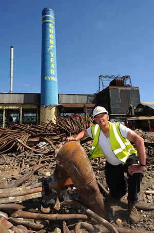 A demolition workeramong the metal remains of a Goodyear boiler
