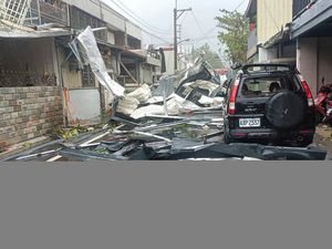 A blown roof destroyed by the wind of Typhoon Kong-rey lies across a road