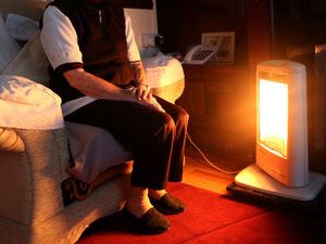 Pensioner sits in front of a heater