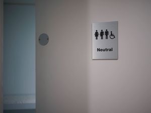A sign on a toilet door depicting three figures and a fourth in a wheelchairgle-sex toilets