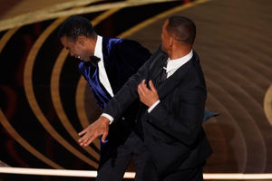 Will Smith, right, hits presenter Chris Rock on stage while presenting the award for best documentary feature at the Oscars on Sunday, March 27, 2022, at the Dolby Theatre in Los Angeles. (AP Photo/Chris Pizzello).