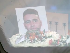 A photograph of Private Sean Rooney surrounded by funeral flowers