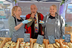 Mayor Mark Whittle taste tests cookies at the Cookies and Whoopies store with sisters Lisa and Debbie Young