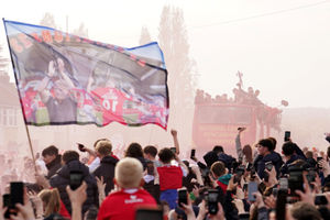Fans wait as the Wrexham victory bus advances through the crowds during a victory parade
